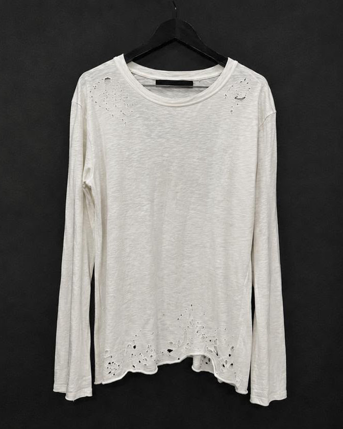A distressed long-sleeve top hanging on black hangers against a dark background. The top is a light off-white color with frayed, ripped details around the shoulders, sleeves, and hem.