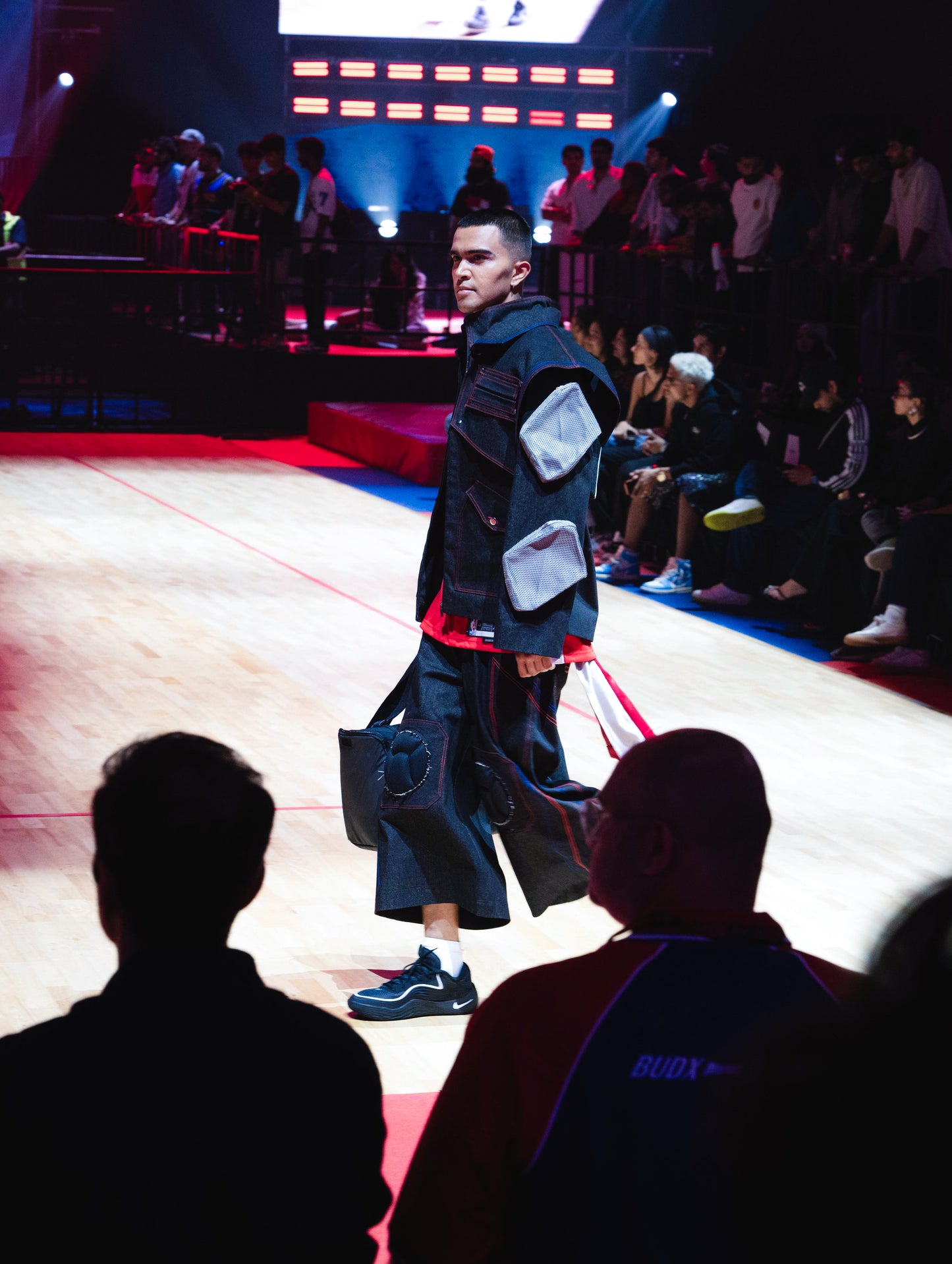 Model walking the ramp at the BUDXNBAHOUSE fashion show wearing Knee Pad Black Denim Jorts