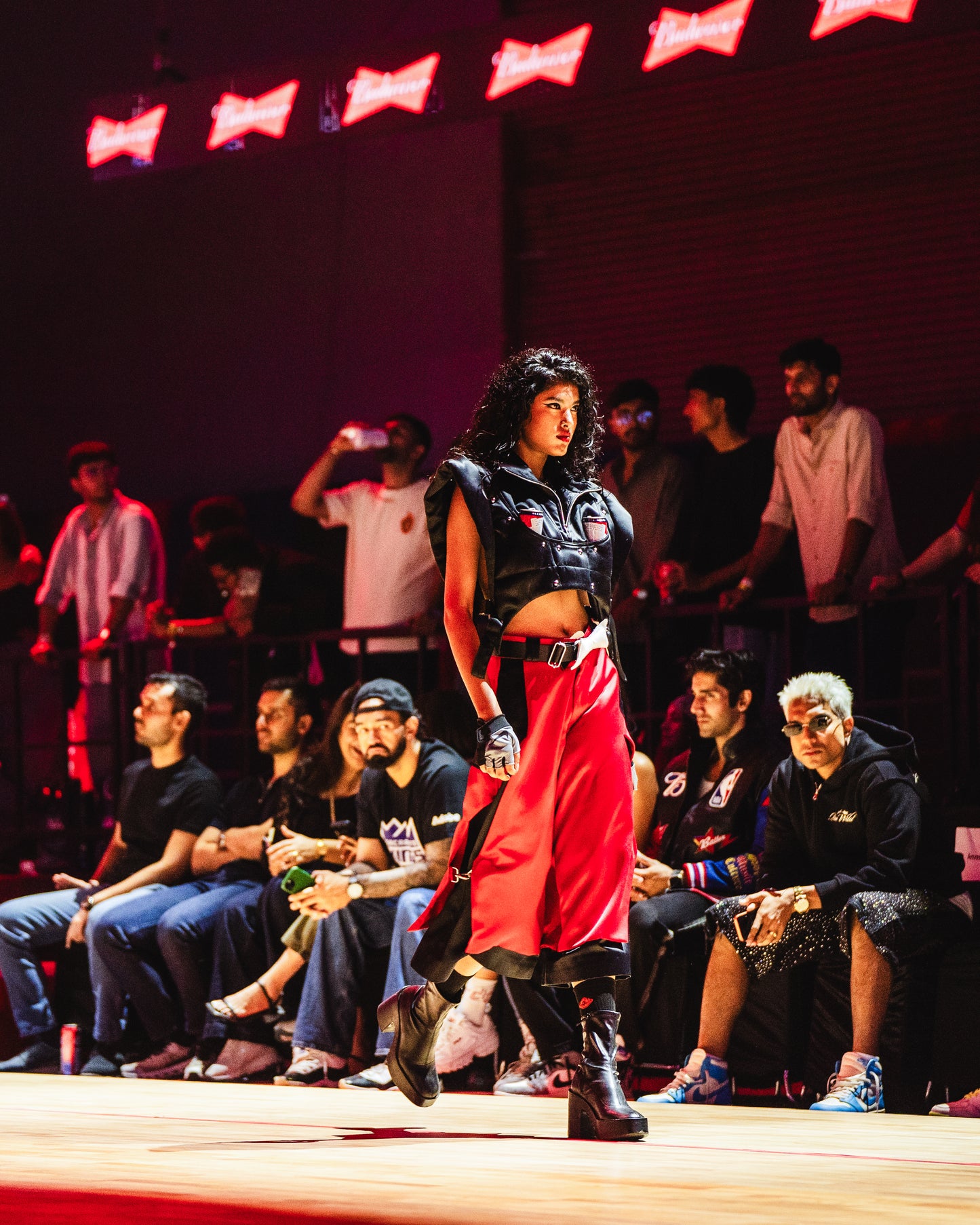 Model walking the ramp at the BUDXNBAHOUSE fashion show wearing Apex Red Black Satin Jorts