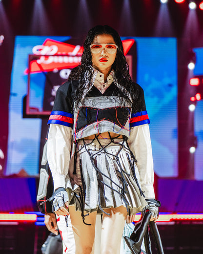 Model walking on a runway at the BUDXNBAHOUSE fashion show wearing Silver Mini SKirt with rivet and ropes detailing.